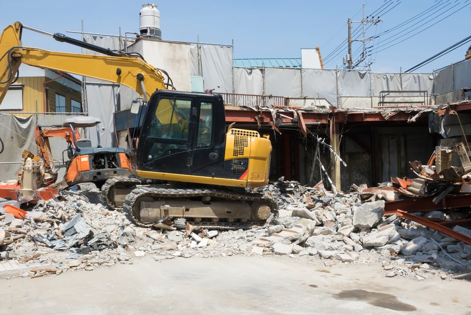 Chantier de démolition en extérieur avec pelleteuses hydrauliques sur chenilles détruisant des bâtiments résidentiels