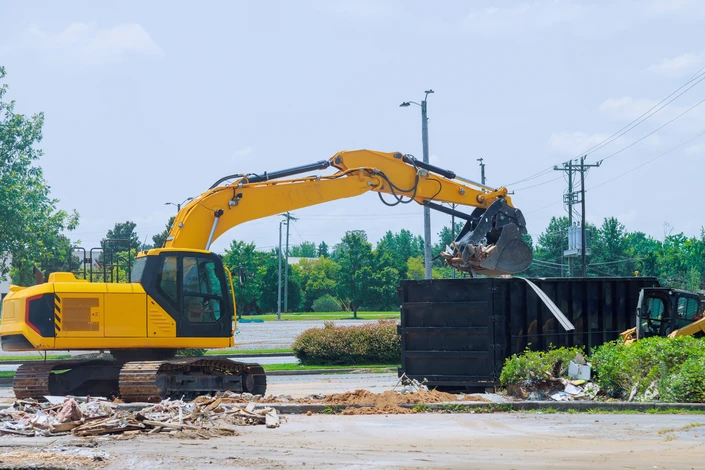 Chantier de démolition en extérieur avec pelleteuse hydraulique orange Doosan 255LCV équipée d'un brise-roche hydraulique détruisant une structure en béton armé