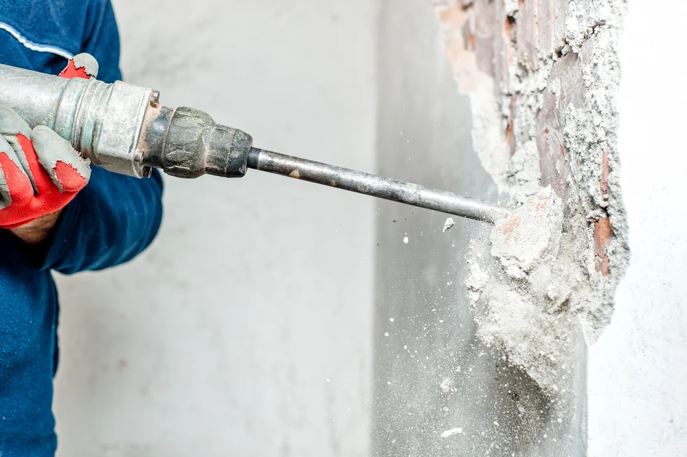 Ouvrier en équipement de protection individuelle scie des blocs de béton cellulaire sur chantier de construction