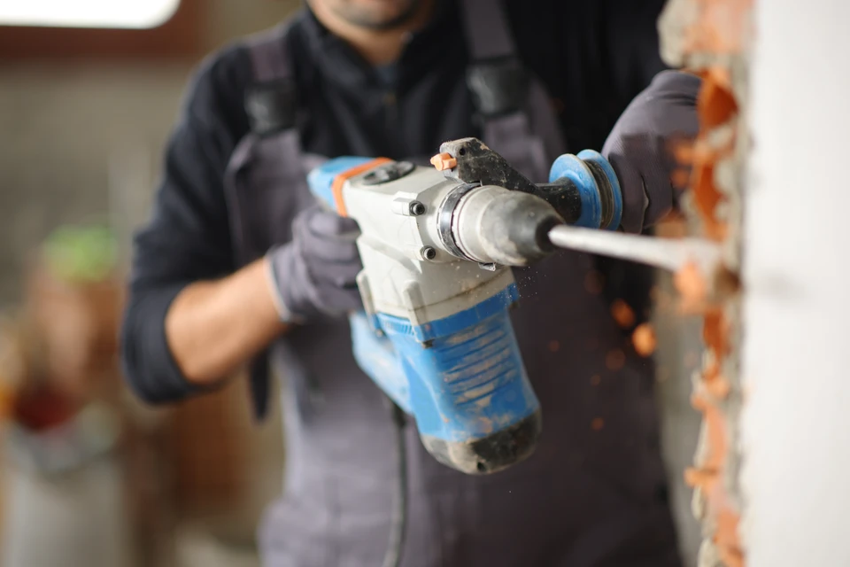 Ouvrier en démolition utilisant un marteau-piqueur pneumatique dans un bâtiment en rénovation